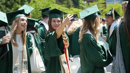 two graduates in cap and gowns pose for a selfie