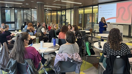 room of people sitting at tables watching a presentation by a career preparation trainer in front of a screen