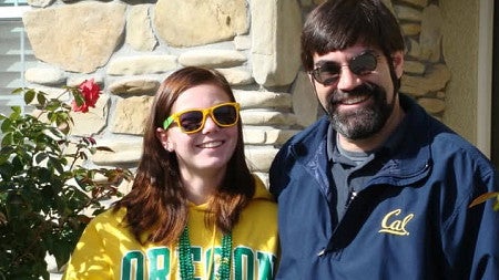 psychology alum mara sargent dressed in university of oregon fan gear standing next to her father dressed in cal berkeley fan gear
