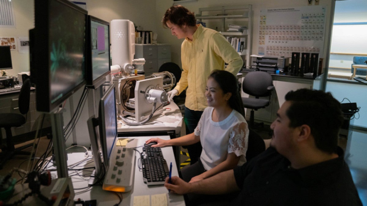 Three people in the School of Computer and Data Science at a computer