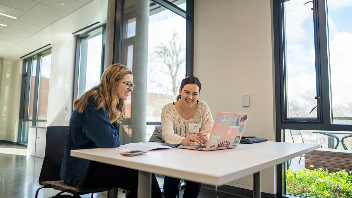 two people at a table smiling at computer