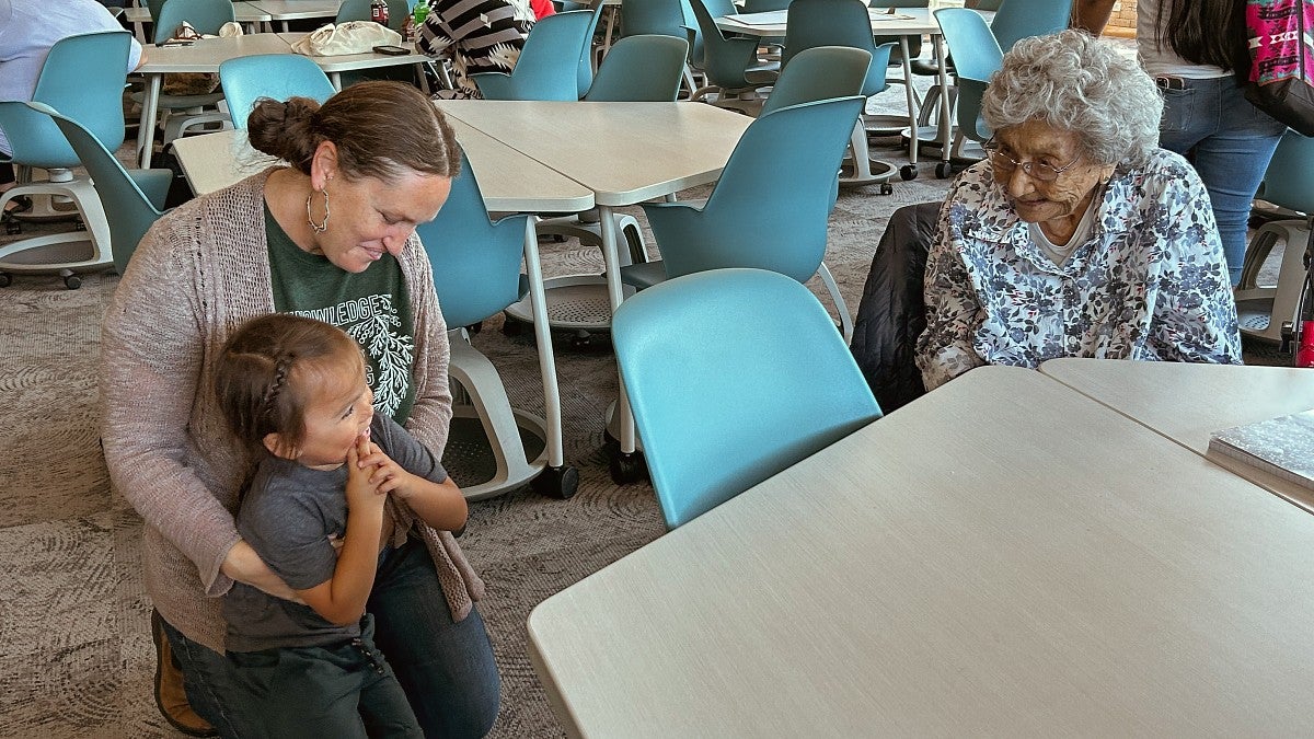 a photo of a woman holding a baby next to an Indigenous elder