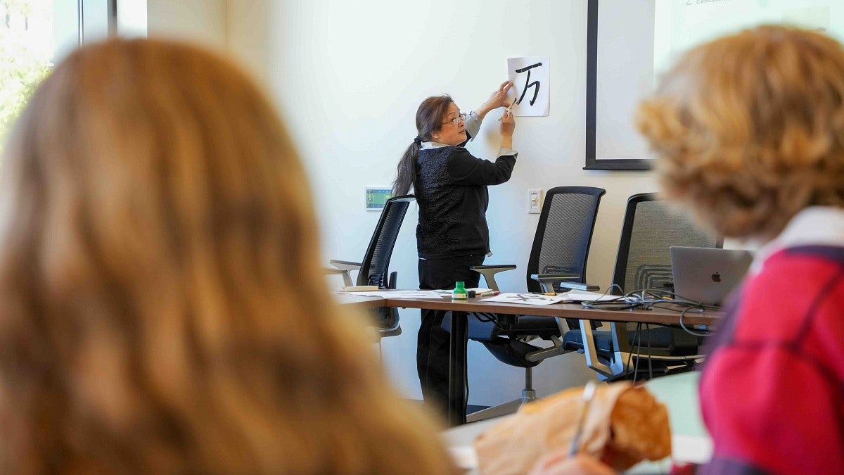 students watching an instructor write chinese calligraphy 