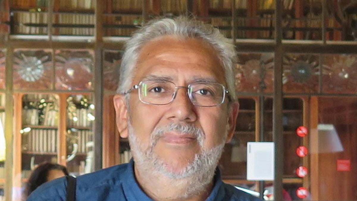 Carlos Aguirre, wearing a blue collar shirt posing in front of an ornate building
