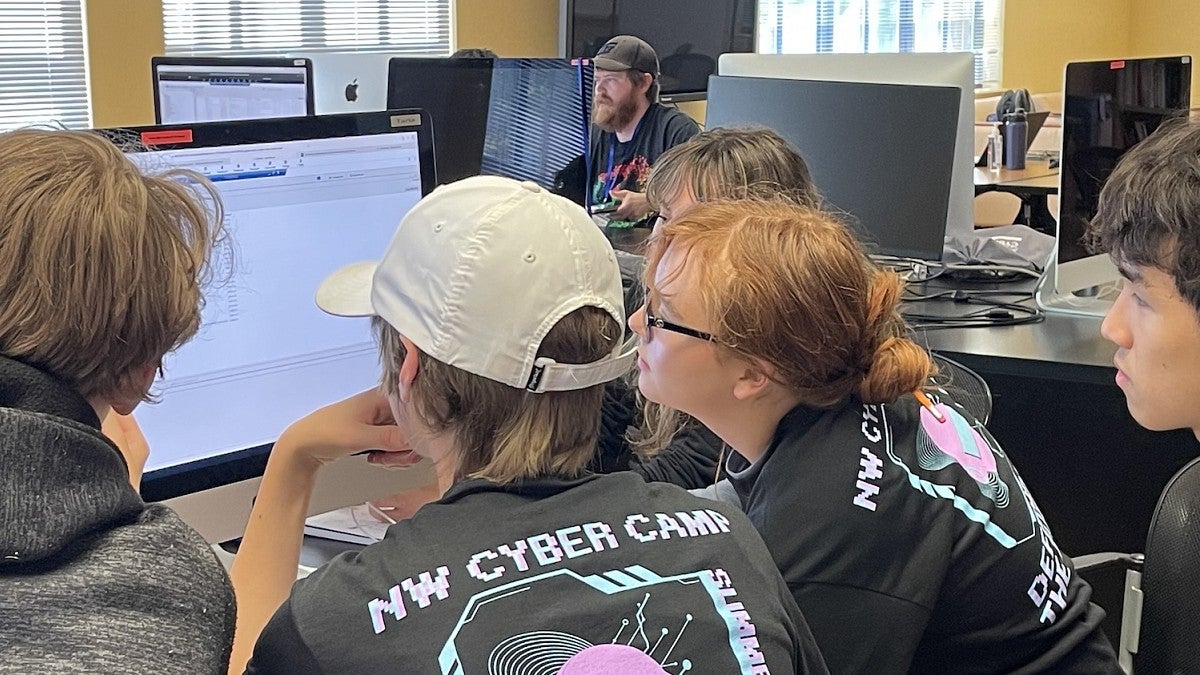 High school students gather around a computer screen