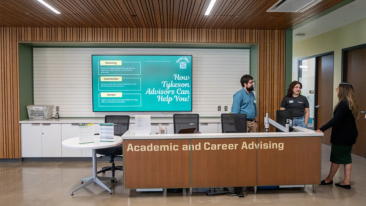 Academic and career advisors standing and talking at a desk