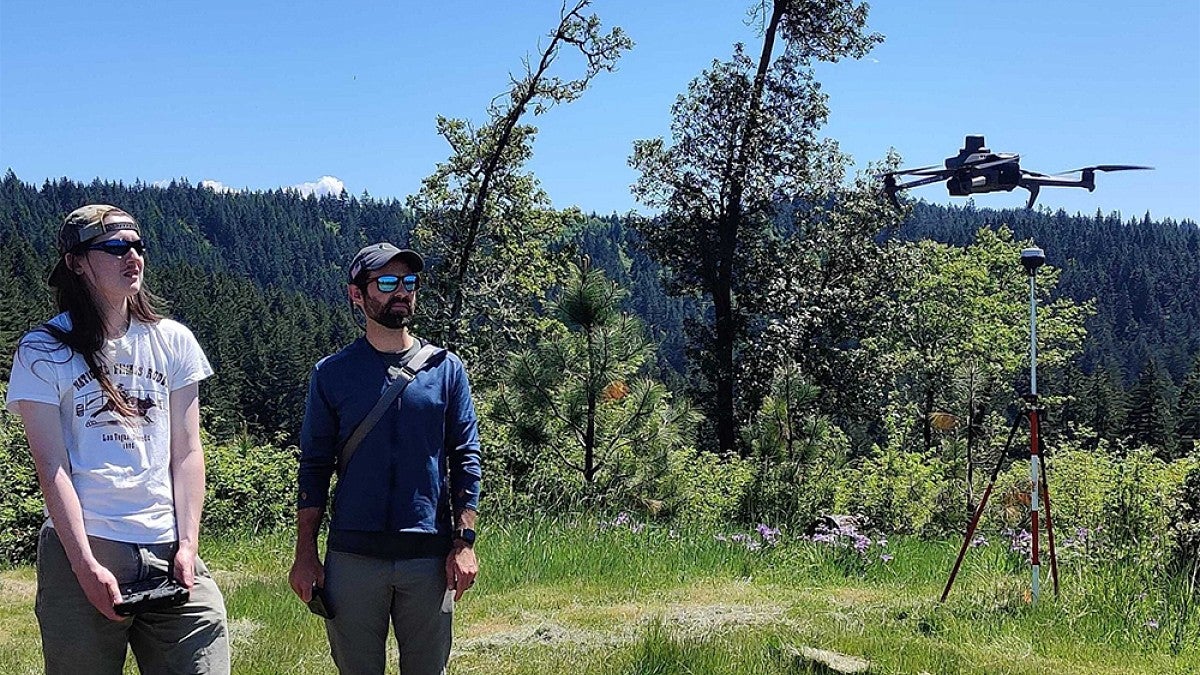 Student standing in a field operating a drone 