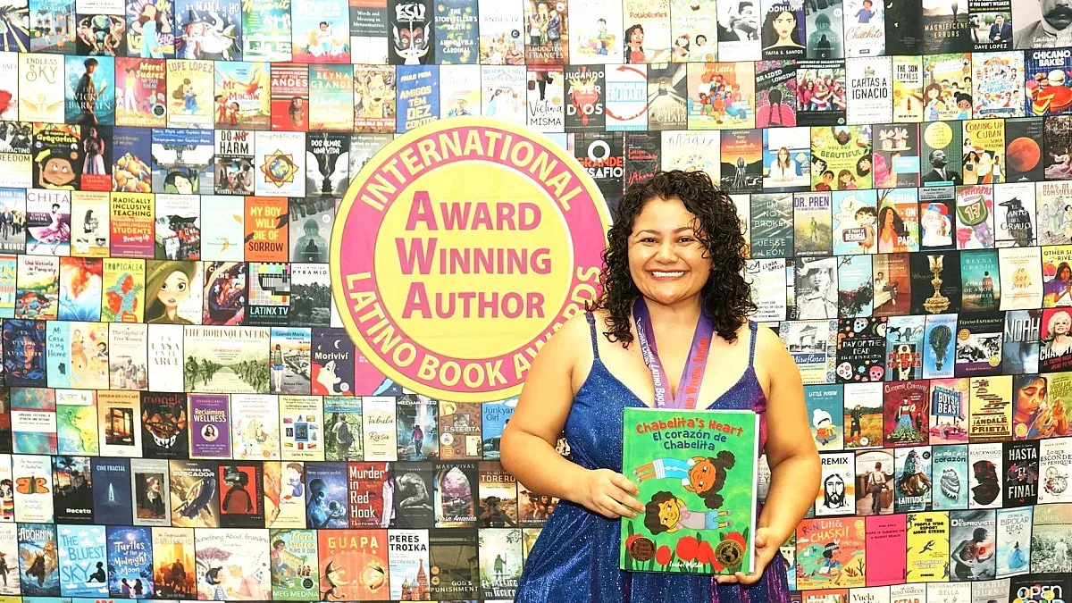 isabel millan stands with her book in front of a background