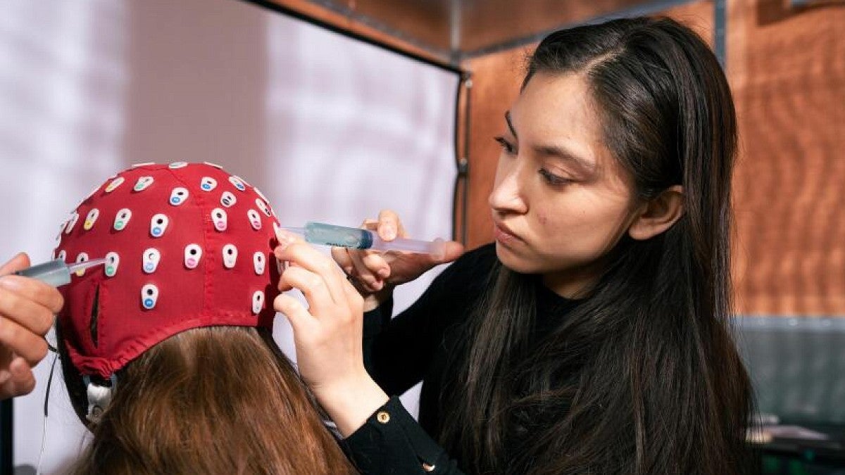 A researcher applying gel to and electrode cap used in tests