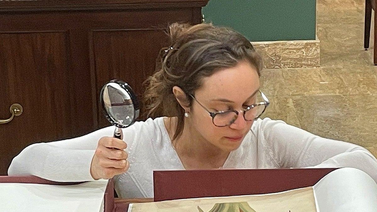 A student studying a manuscript with a magnifying glass