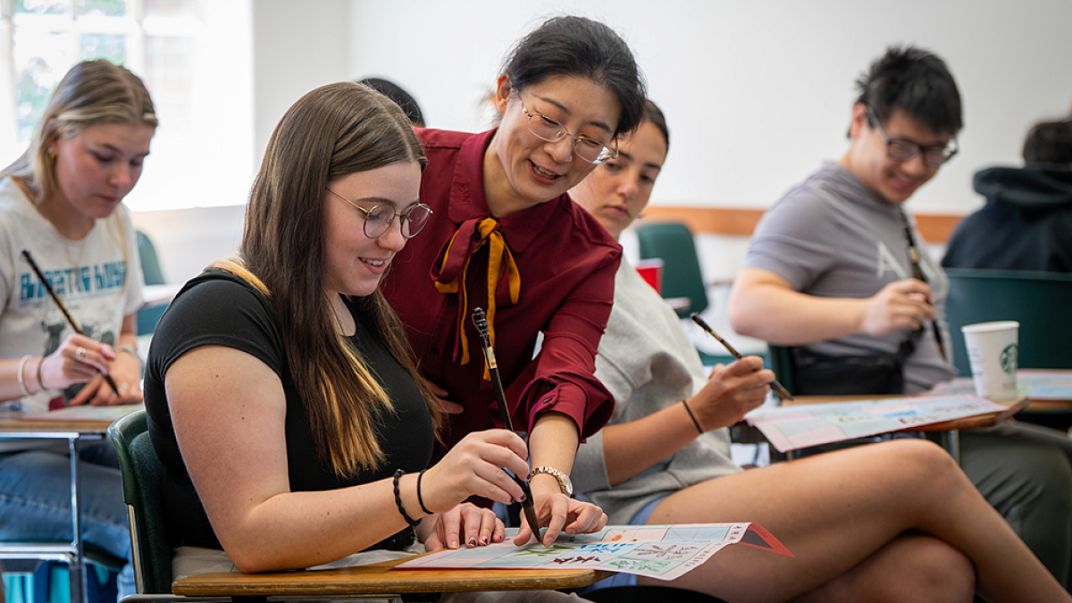 A teacher instructing a student sitting at a desk