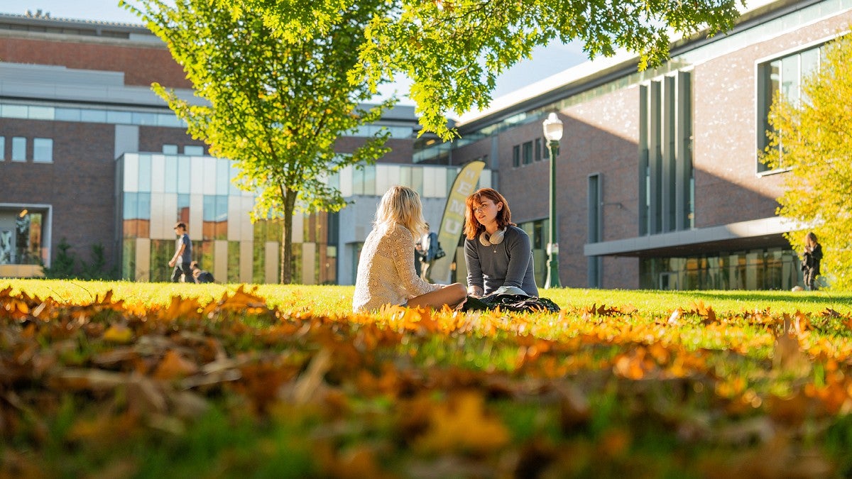 Two students sitting on campus lawn