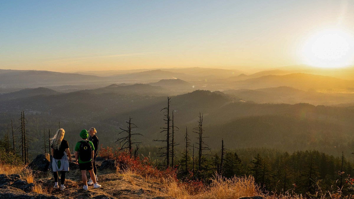 people standing on top of a mountain with the sunset in the background
