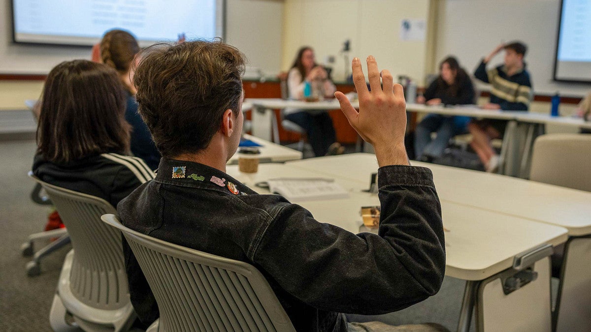 a person raises their hand in a small classroom setting