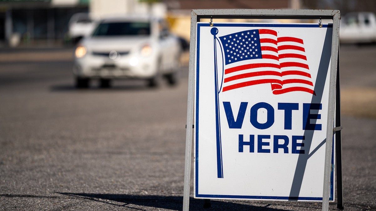 vote here sign in parking lot with article about election issues of 2026