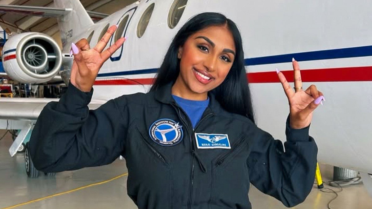 a person posing in front of an aircraft wearing a jumpsuit