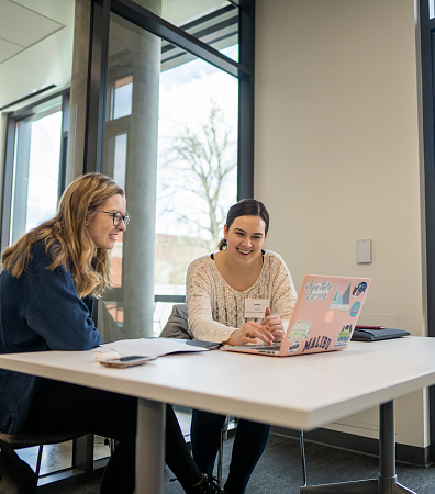 two people at a table smiling at computer