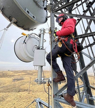 A person climbing a tower installing equipment