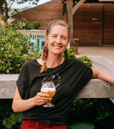 cas alum annie pollard sitting on a bench holding a beer