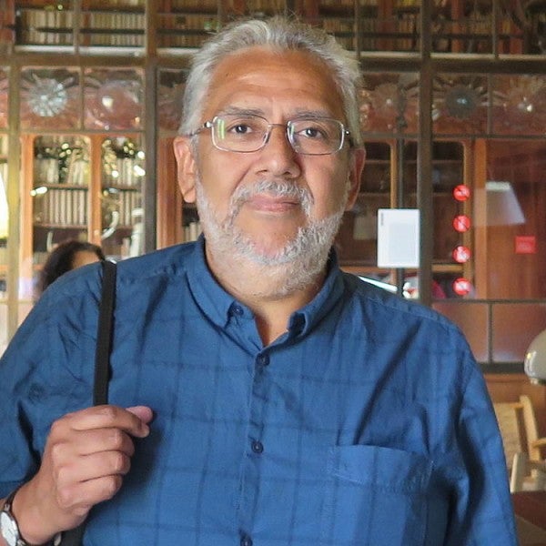 Carlos Aguirre, wearing a blue collar shirt posing in front of an ornate building