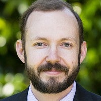 Man in front of a leafy background